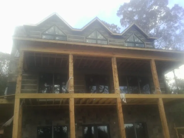 Dormers and porch framing on a large log home under construction — Roof Coating work by our crew in Sciota