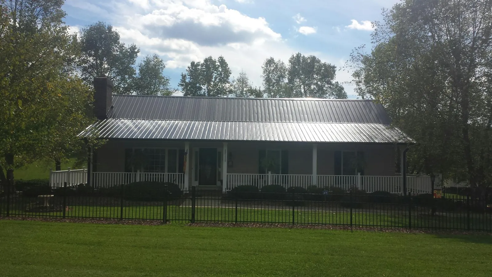 Gray metal roof on a brick ranch with a full width front porch — Gutter Guard Installation work by our crew in Sciota