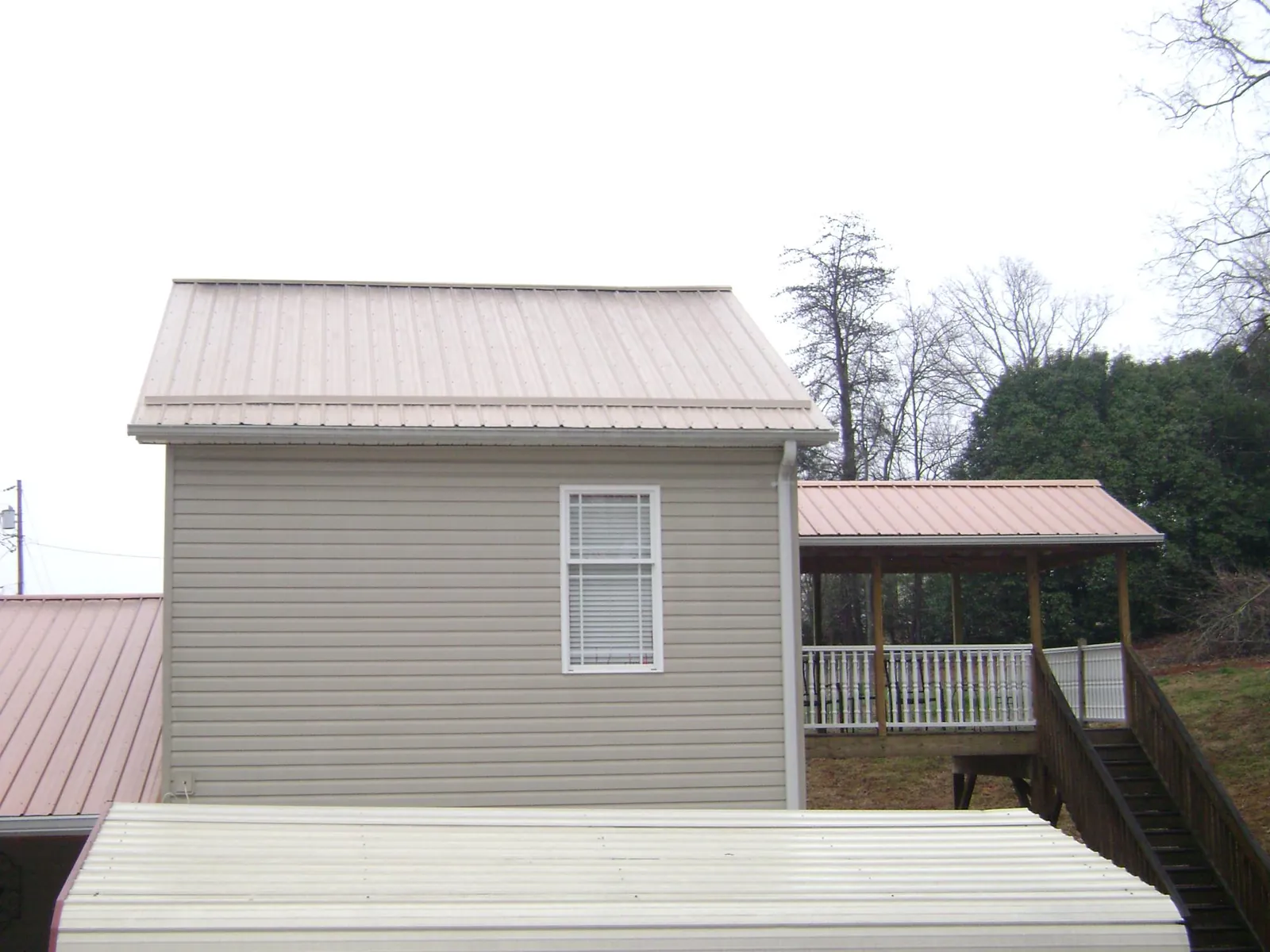 Tan metal roofs on a two story addition and attached porch, from a Roof Replacement job in Sciota
