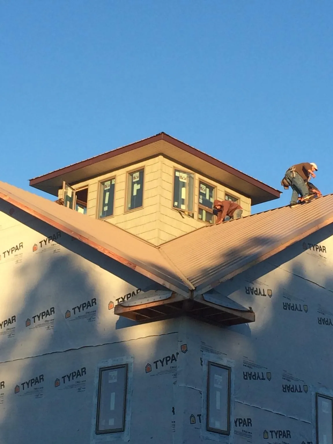 Roofers working around a rooftop cupola on a new metal roof at sunset — Roof Waterproofing in Sciota by Roofing Brothers